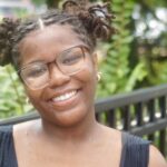 A girl with glasses smiling at a camera