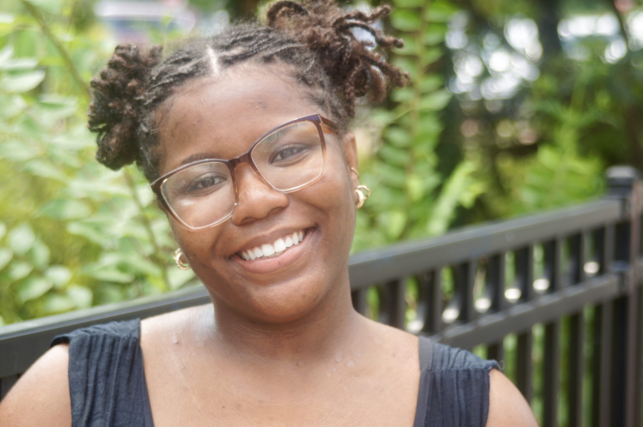 A girl with glasses smiling at a camera